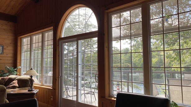A cozy room with large windows, a wooden ceiling, and a view of the outdoors. - Diamonds On The Bay (Greenfield)