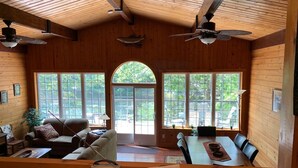 A cozy cabin interior with wooden walls, a dining area, and a living room with a sofa and chairs. - Diamonds On The Bay (Greenfield)