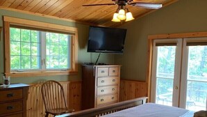 A bedroom with a bed, dresser, television, and windows. - Diamonds On The Bay (Greenfield)