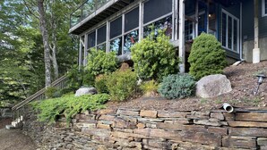 A stone retaining wall with a staircase leading to a building with large windows and a balcony. - Diamonds On The Bay (Greenfield)
