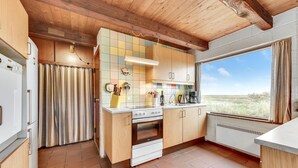 A compact kitchen with wooden cabinets, a stove, and a window with a view of the outdoors.