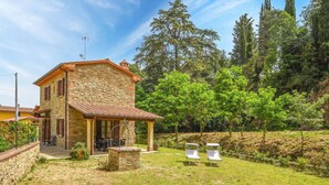 Une maison en pierre dotée d’un patio, d’un espace salon extérieur et d’un jardin.