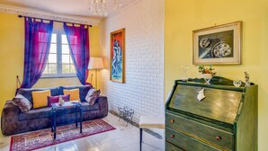 Een woonkamer met een bank, een salontafel, een kroonluchter, een schilderij en een dressoir.