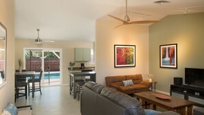A spacious living area with a sofa, a coffee table, and a TV. There is a dining area with chairs and a table. - Pool, Hot tub, Fire Pit, BBQ ~  Beautiful home with patio living at it's best! (Cottonwood)