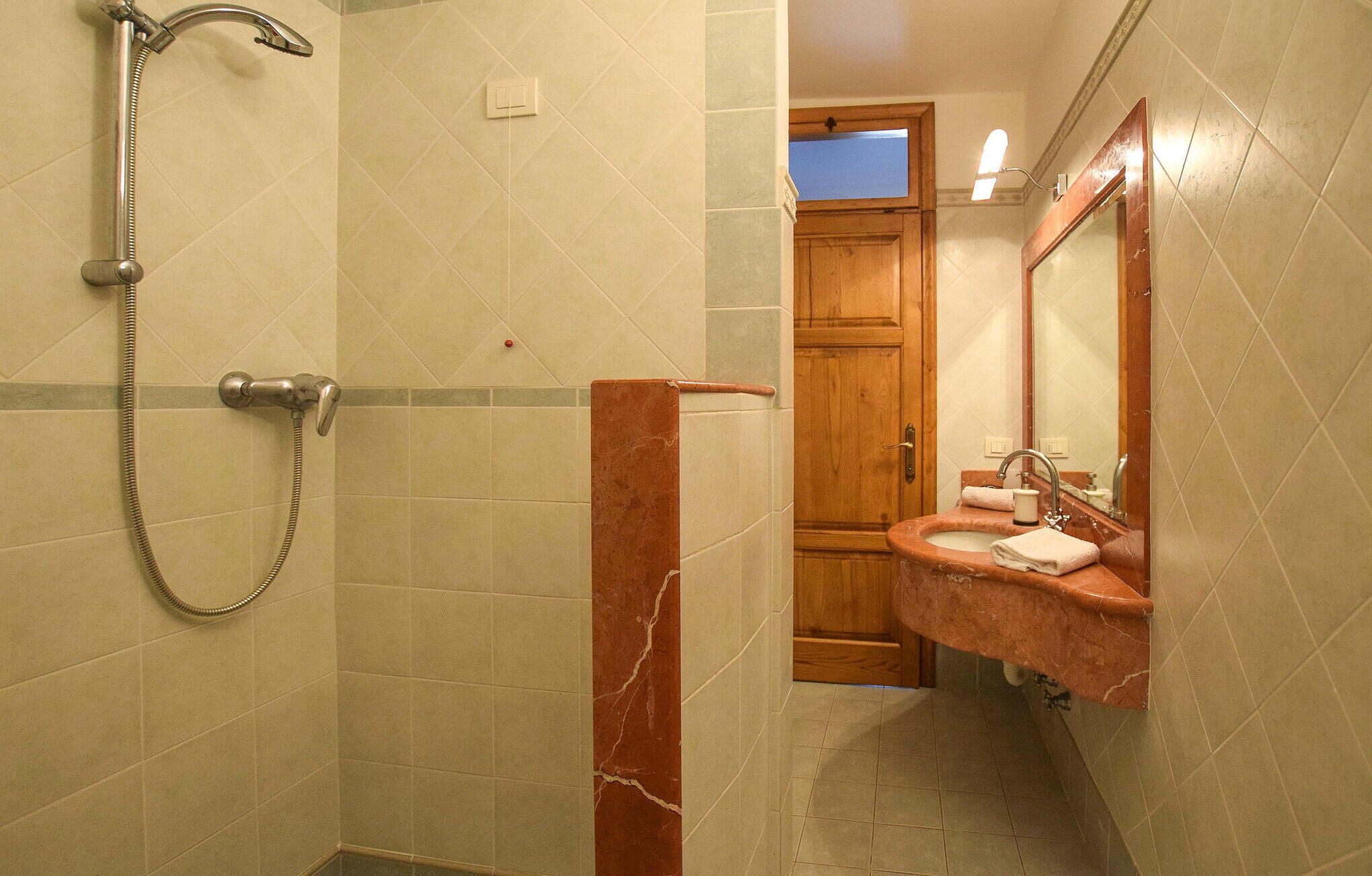 Un baño con ducha, lavamanos y espejo.