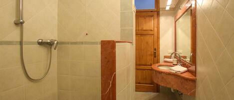 Un baño con ducha, lavamanos y espejo.