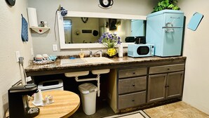 A compact kitchen with a sink, countertop, microwave, and a small refrigerator. - Deluxe Single Queen Suite Futon & Kitchenette (Salmon)