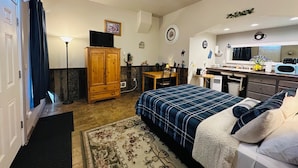 A compact room with a bed, a desk, a kitchenette, and a wardrobe. - Deluxe Single Queen Suite Futon & Kitchenette (Salmon)