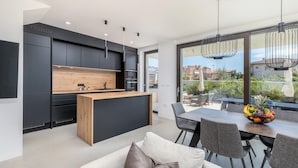 Una cucina moderna con mobili scuri, un piano di lavoro in legno e un'area pranzo con tavolo e sedie.