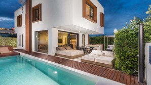Una moderna casa a due piani con piscina, area salotto esterna e giardino curato.