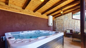 Un jacuzzi en una cabaña rústica con paredes de piedra y vigas de madera.