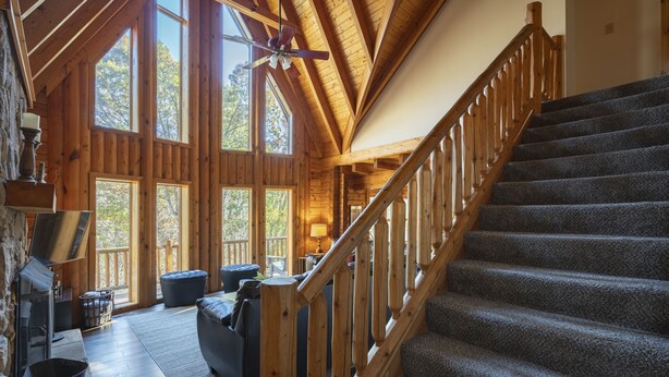 A wooden cabin interior with a staircase, large windows, and a fireplace. - ❤️ of Hocking Hills 🌲 Hot Tub, Wifi, Close to Trails + Caves, 11 Secluded Acres (South Bloomingville)