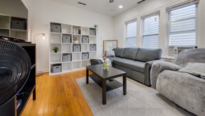 Un salon avec une table basse en bois foncé, un canapé gris et un ventilateur de plafond.