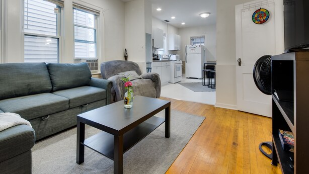 Un salon moderne avec un canapé gris, une table basse et un ventilateur.