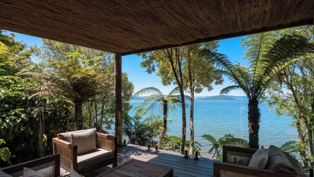 A covered outdoor seating area with wooden furniture and a view of a lake and distant mountains. - Toka Ridge 1bd Lake View Lux Villa w/ HotTub (Hamurana)