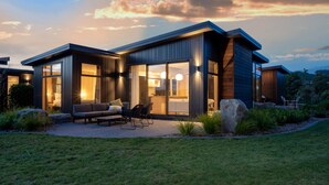 A modern house with a patio, large windows, and a well-maintained lawn. - Toka Ridge Lake View, Lux Villa 2bd2bth w/ HotTub (Hamurana)