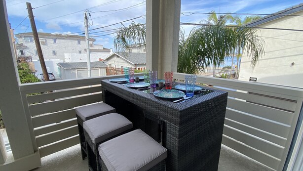 A balcony with a table set for dining, featuring glassware and plates.