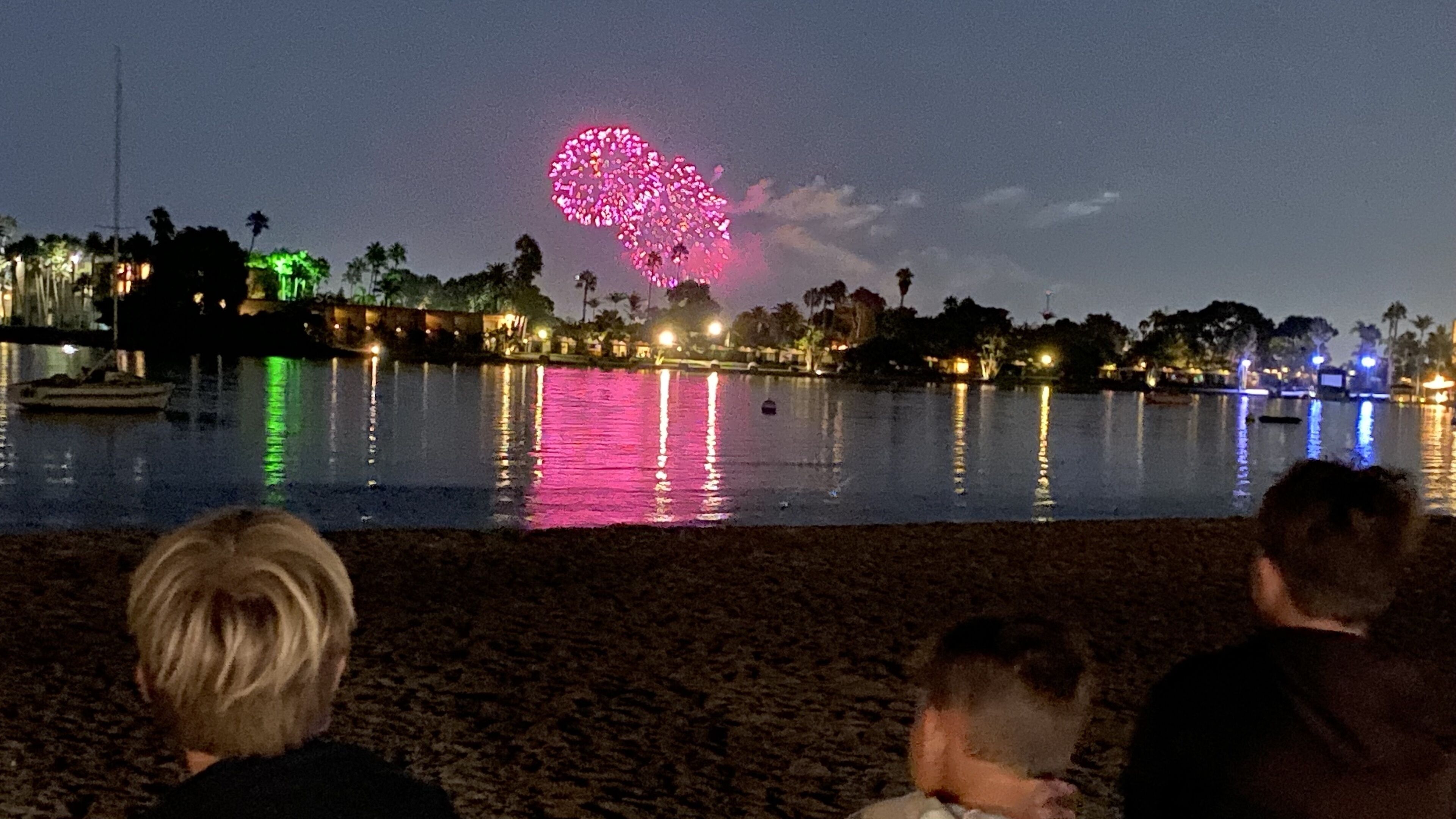 A nighttime view of a lake with a fireworks display.
