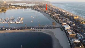 An aerial view of a coastal town with a marina, residential buildings, and a beach.