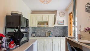 Una cocina compacta con gabinetes blancos, un microondas, una estufa y un lavamanos.