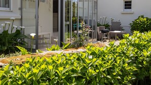 Una casa moderna con un invernadero de vidrio, mobiliario exterior y un jardín.