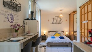 Una habitación de hotel pequeña con una cama, mesita de noche y una pequeña zona de escritorio con una silla.