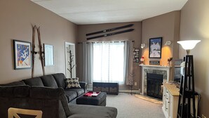 A living room with a sofa, a coffee table, a fireplace, and a lamp.