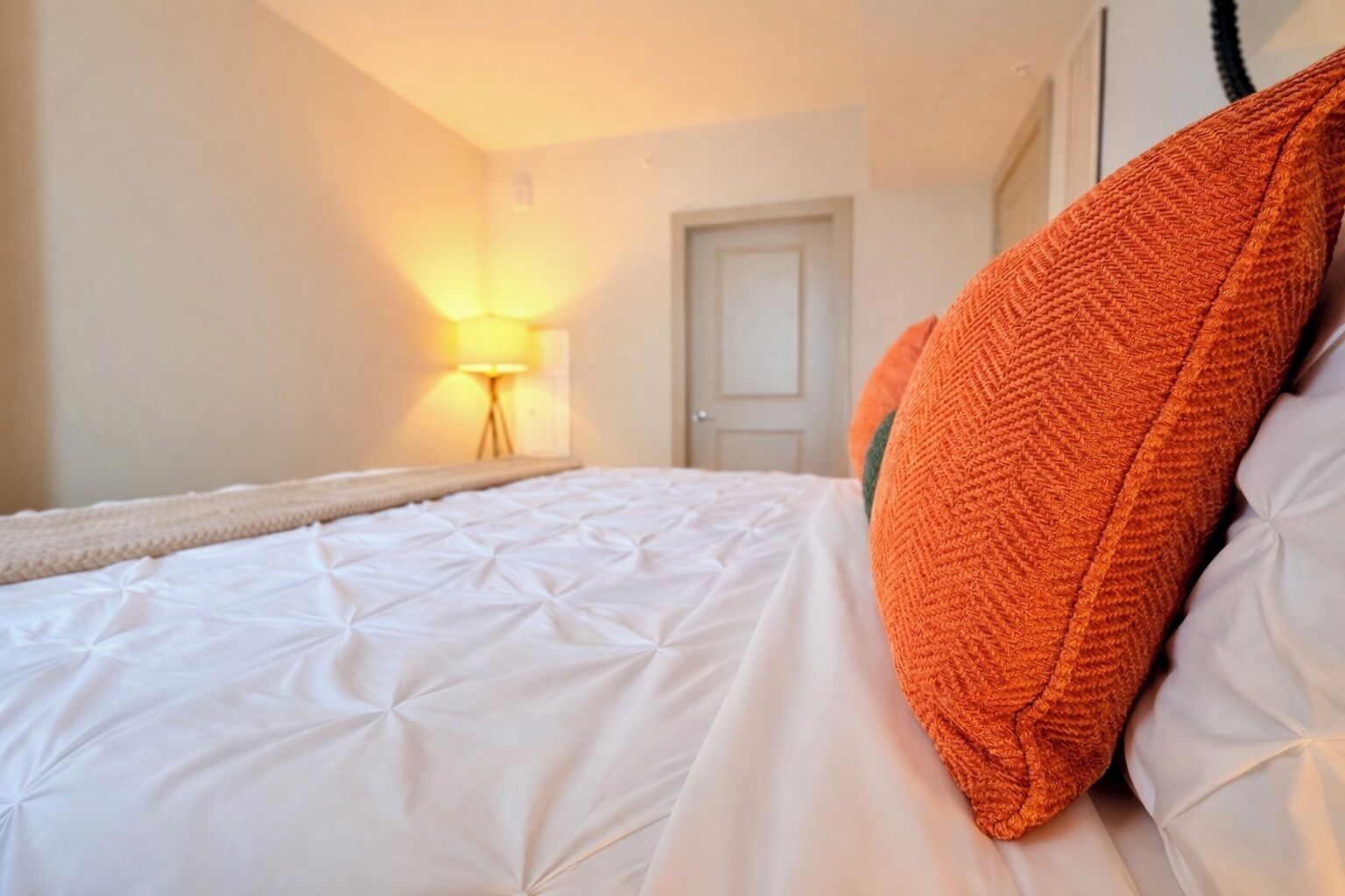 Una camera d'albergo con un letto, una lampada e una porta.
