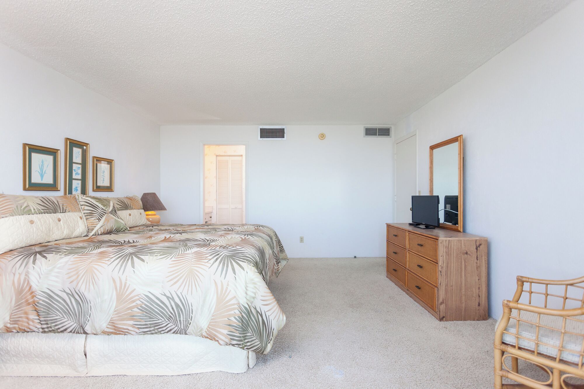 A bedroom with a bed, a dresser, a television, and a chair.