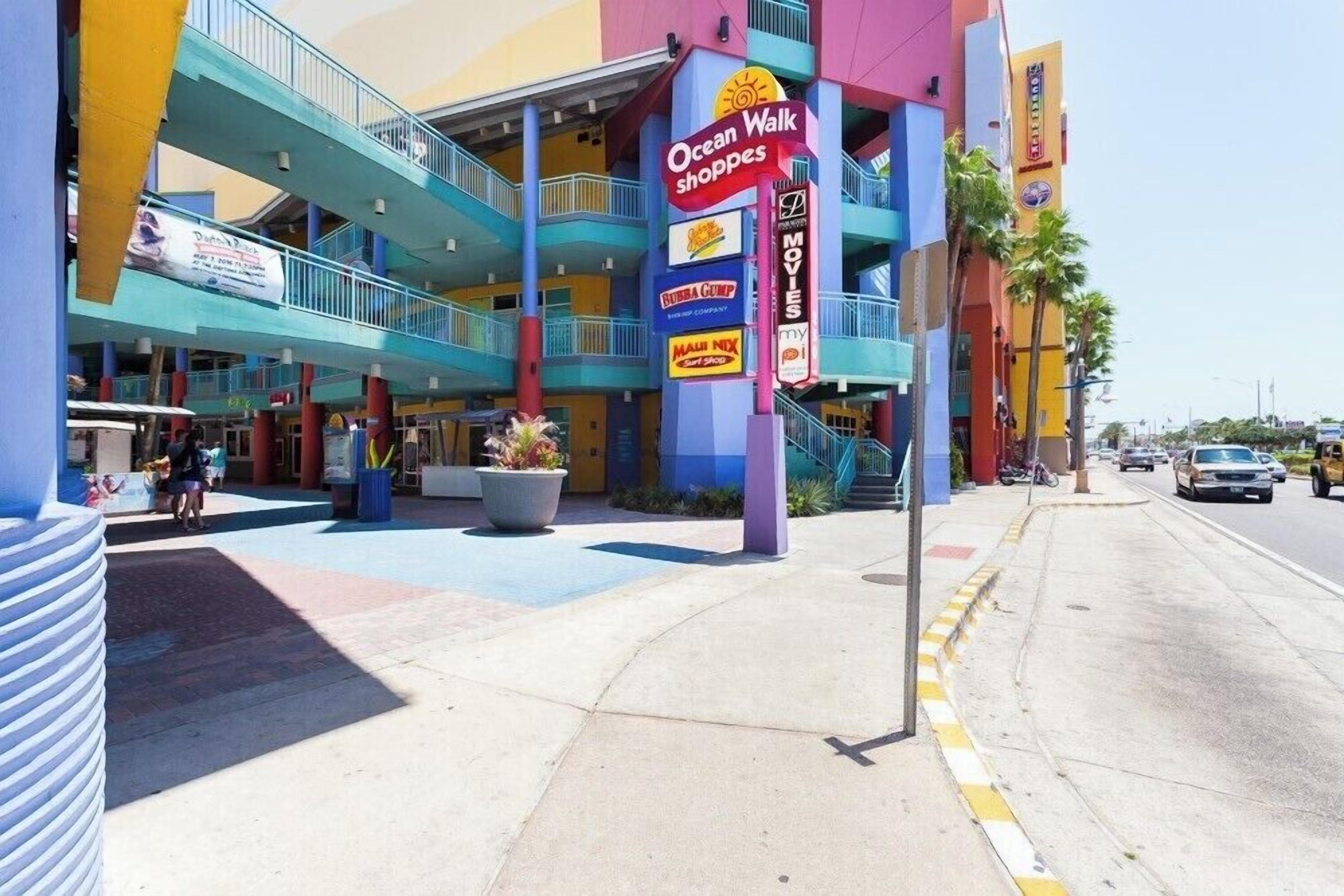 A multi-story building with a colorful facade, featuring signs for Ocean Walk Shoppers and other businesses.