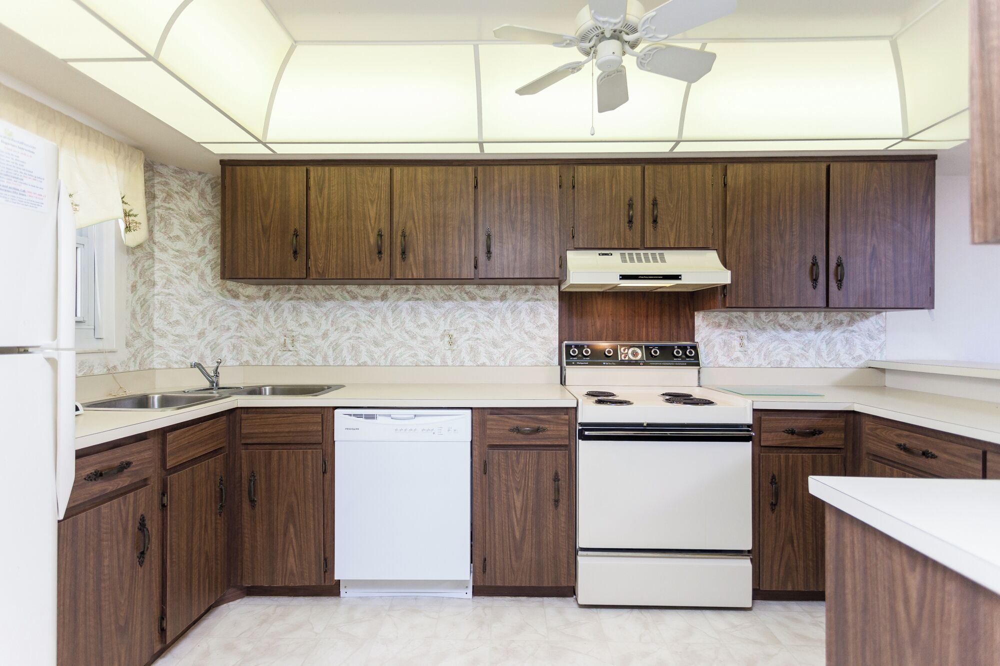 A kitchen with wooden cabinets, a white stove, and a ceiling fan.