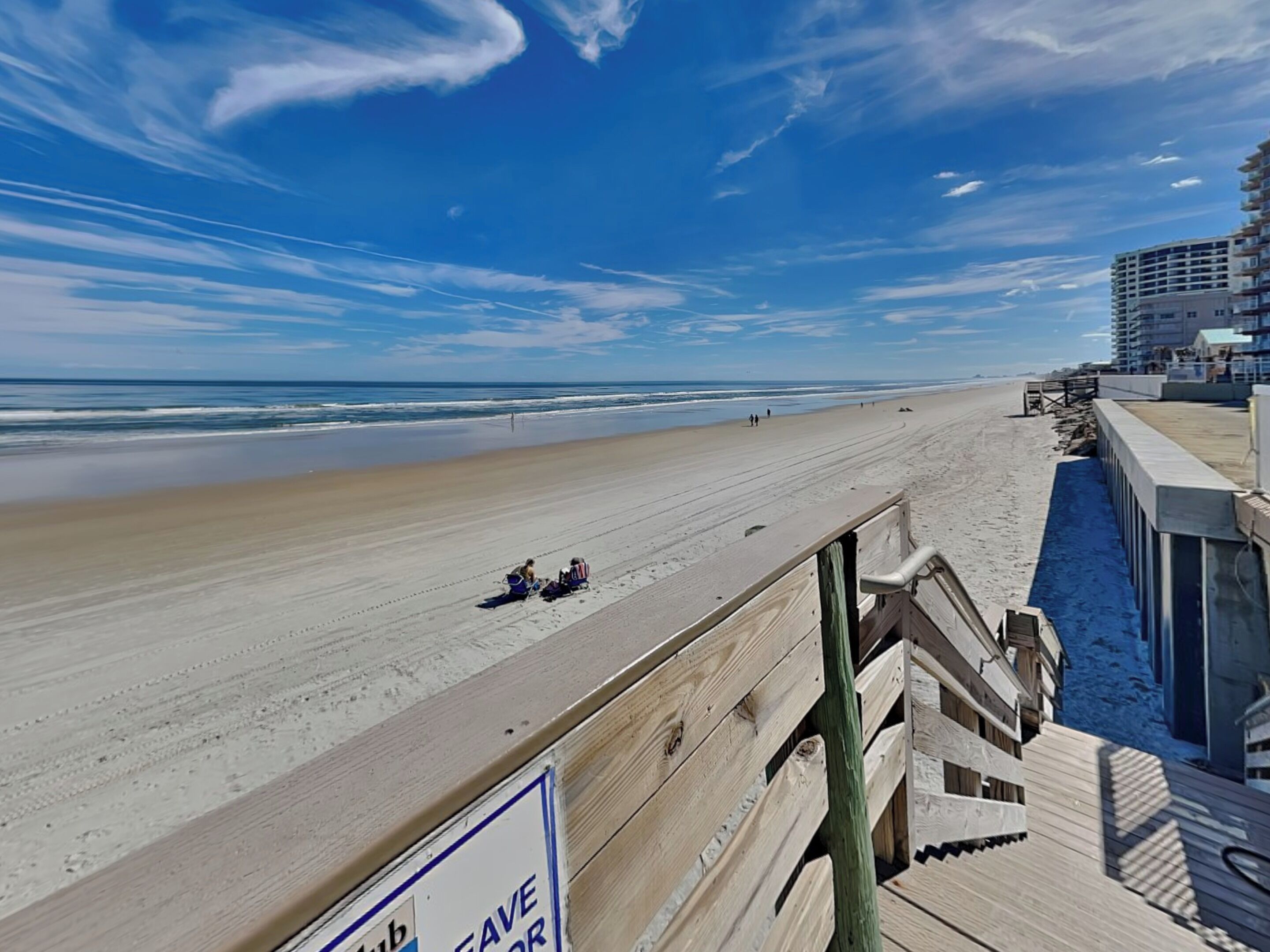 Une plage avec une promenade en bois et un panneau indiquant « ÉPARGNEZ POUR ».