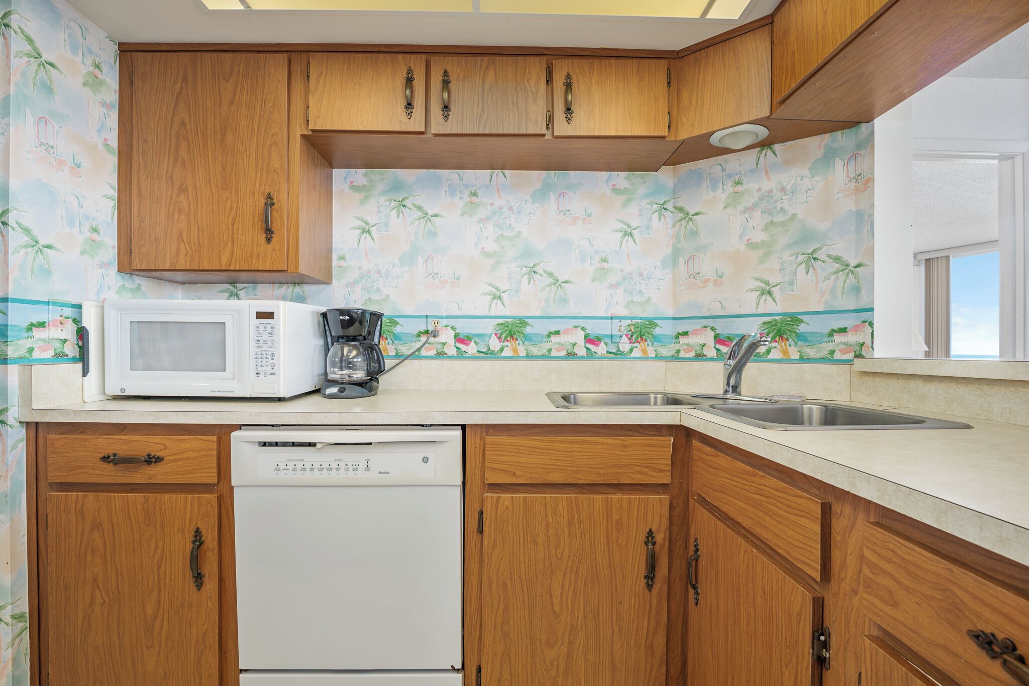 A kitchen with wooden cabinets, a microwave, a coffee maker, and a dishwasher.