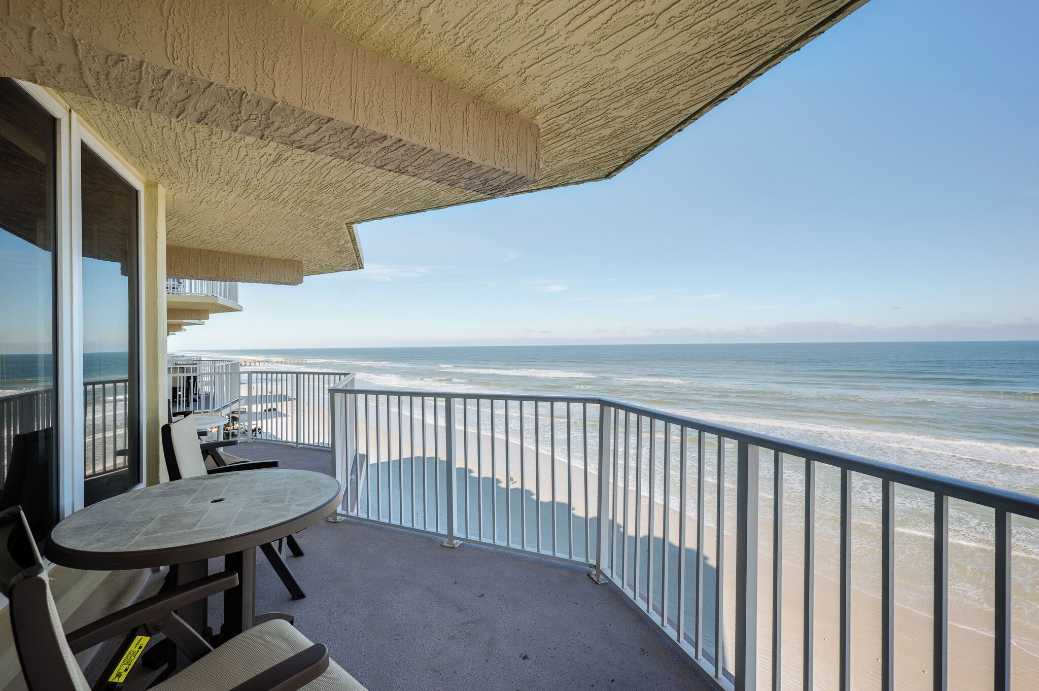 A balcony with a view of the beach and ocean.