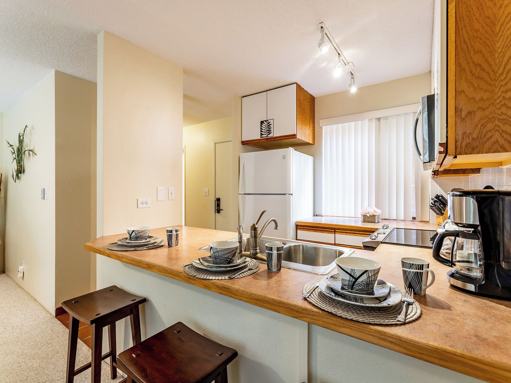 A modern kitchen with a wooden countertop, stainless steel sink, and a coffee maker.