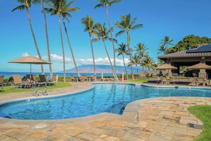 A swimming pool with lounge chairs and umbrellas, surrounded by palm trees and a view of the ocean. - Wailea Ekahi by Maui Rental Group (Kihei)