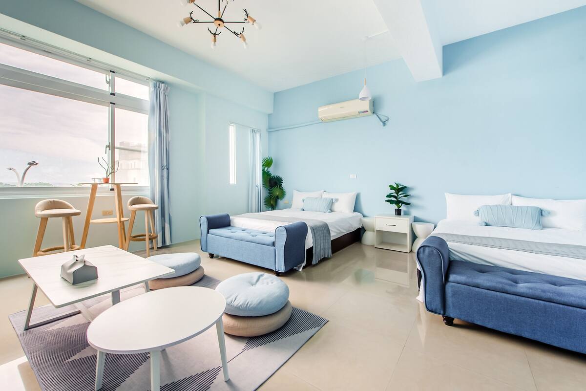 A modern bedroom with a large bed, two smaller beds, a desk, and a chair.