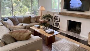 A modern living room with a sofa, coffee table, fireplace, and a TV mounted on the wall. - THE Zen Treehouse Retreat- Great Views and Peaceful Decks!
 (Los Angeles)