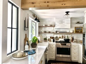 A modern kitchen with white cabinetry, a large island, stainless steel appliances, and a view of the outdoors. - THE Zen Treehouse Retreat- Great Views and Peaceful Decks!
(Los Angeles)