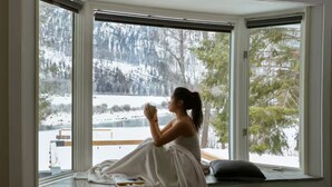 Una persona seduta vicino a una finestra con vista su un paesaggio innevato.