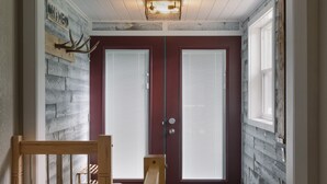 A hallway with a wooden bench, a double door with frosted glass panels, and a light fixture on the ceiling. - All-Season Family Retreat • Hot Tub • Waterfront (Moyie)
