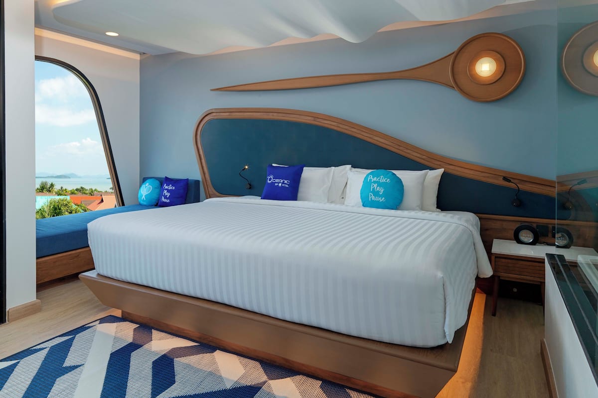 A modern bedroom with a large bed, a view of the outdoors, and a unique ceiling design.