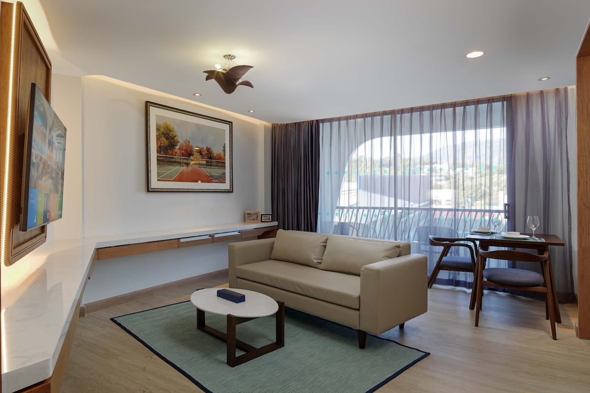 A modern living room with a sofa, a small table, and a dining area with chairs.