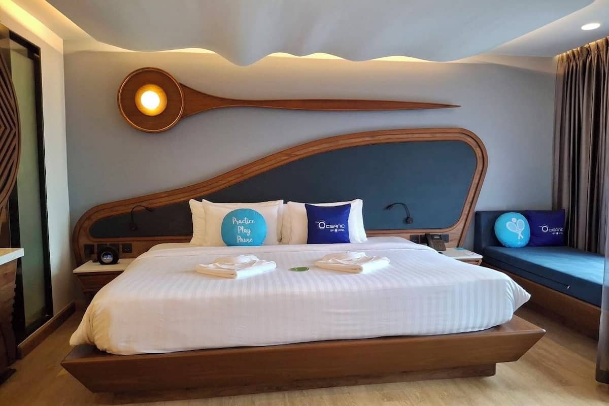 A modern hotel room with a large bed, a wooden headboard, and a unique ceiling design.