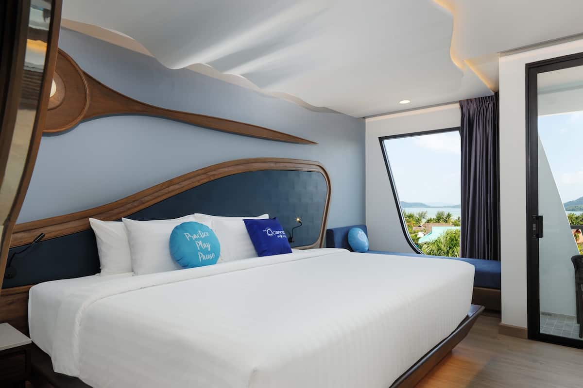 A modern hotel room with a large bed, a curved ceiling, and a view of the sea.