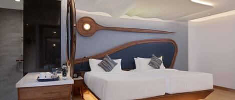 A modern bedroom with a large bed, wooden headboard, bedside tables, and a built-in desk with a mirror.