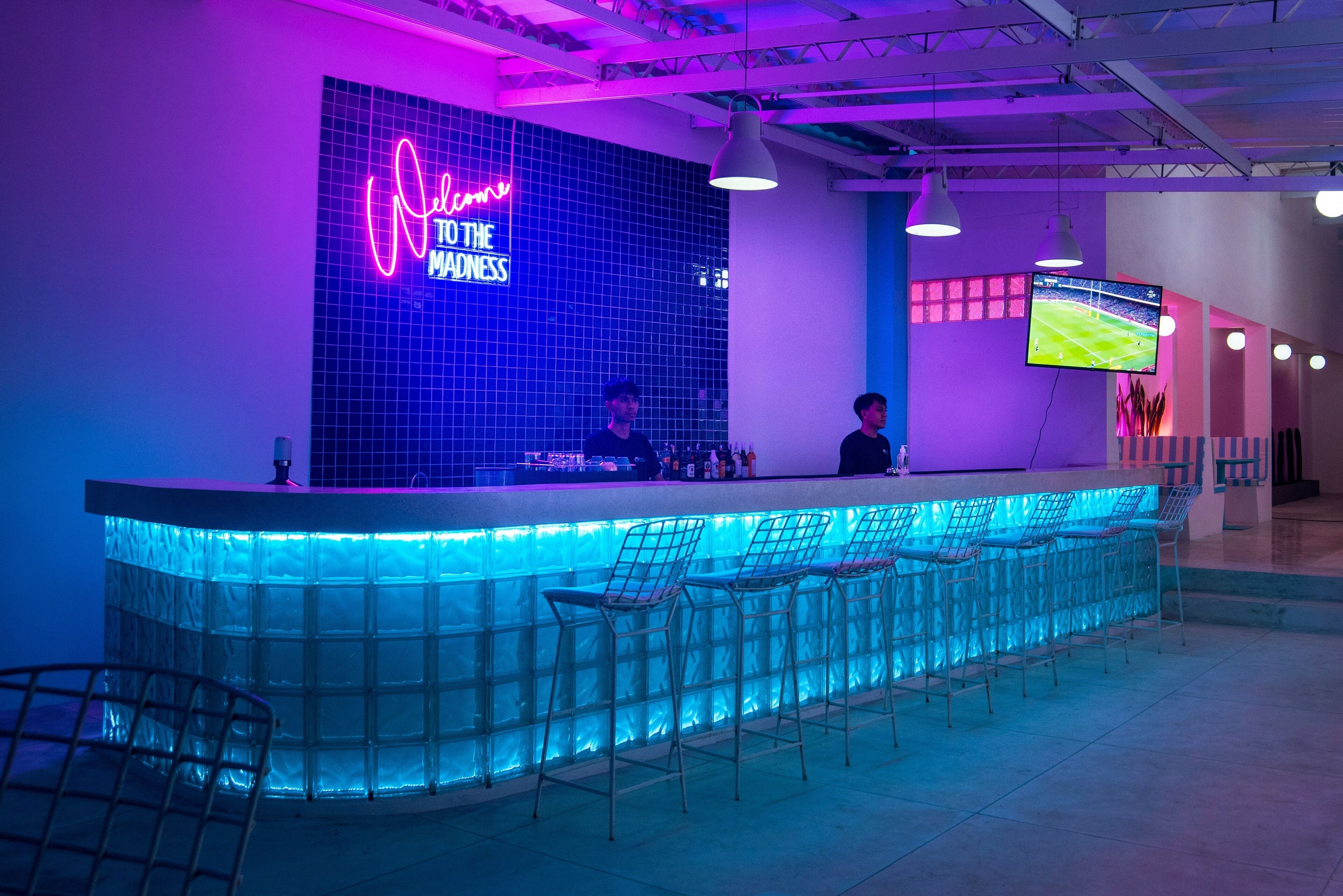Un espace bar agrémenté d'enseignes au néon, de tabourets de bar et d'un écran de télévision.