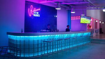 Un espace bar agrémenté d'enseignes au néon, de tabourets de bar et d'un écran de télévision.