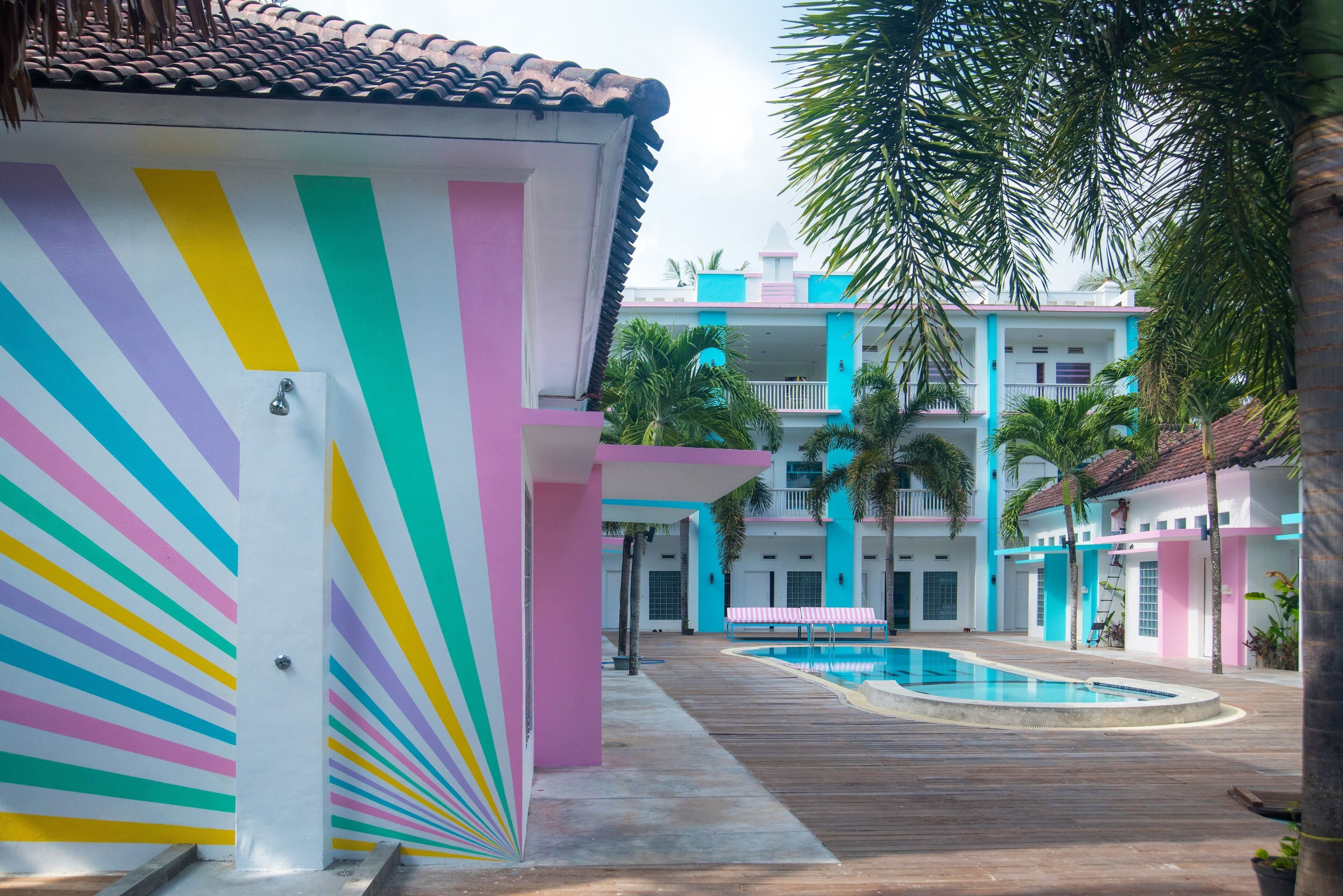 Un edificio colorido con piscina y palmeras.