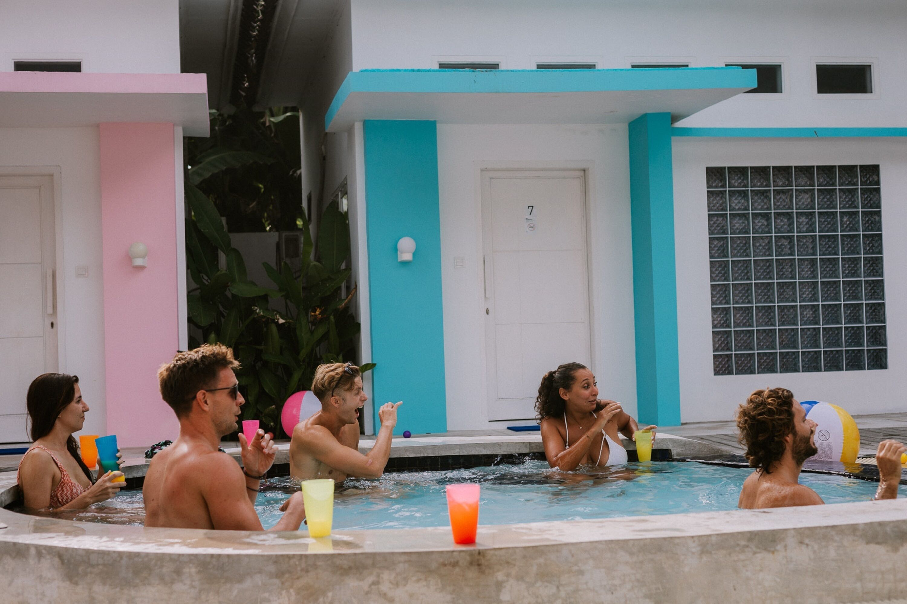 A group of people in a swimming pool with a building in the background.